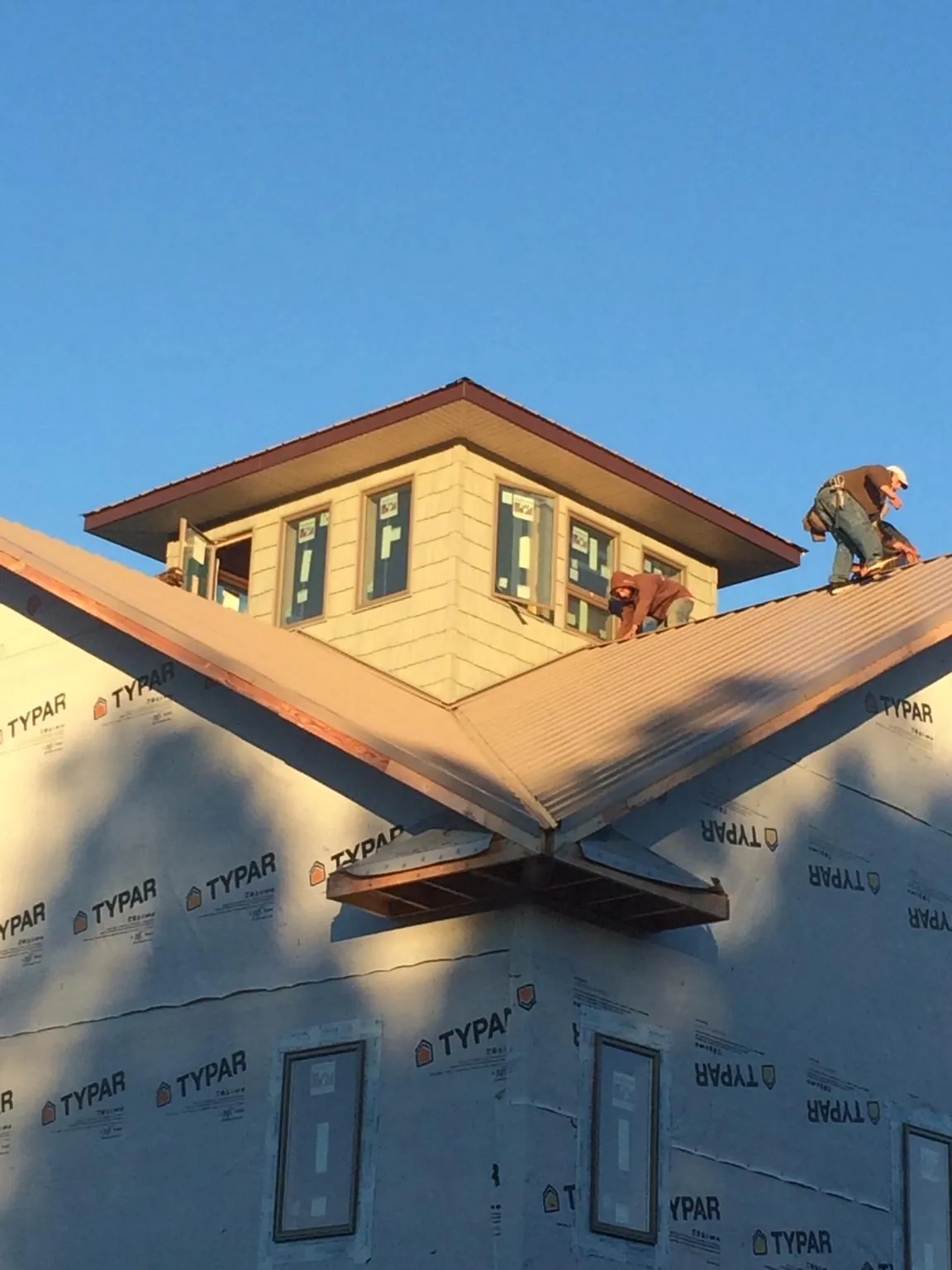 Roofers working around a rooftop cupola on a new metal roof at sunset — Roof Waterproofing in Sheridan by Roofing Brothers